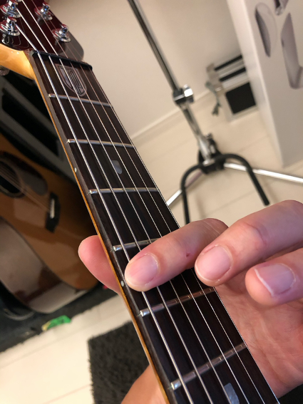 人差し指を6弦5フレットAのポジションで押さえる